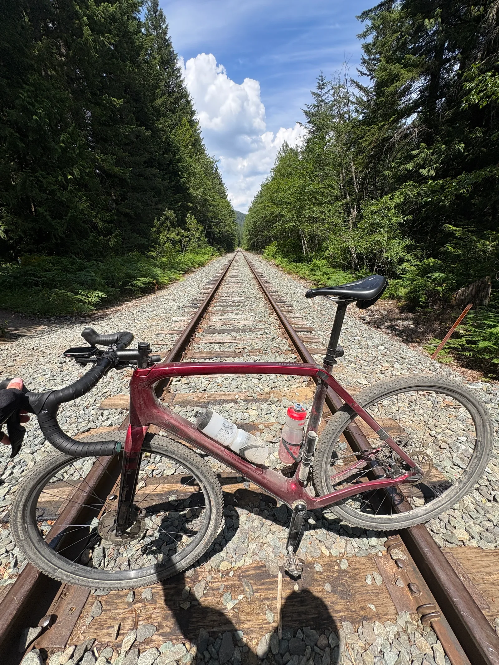 Gravel bike laid across old railway tracks with two water bottles visible in the frame