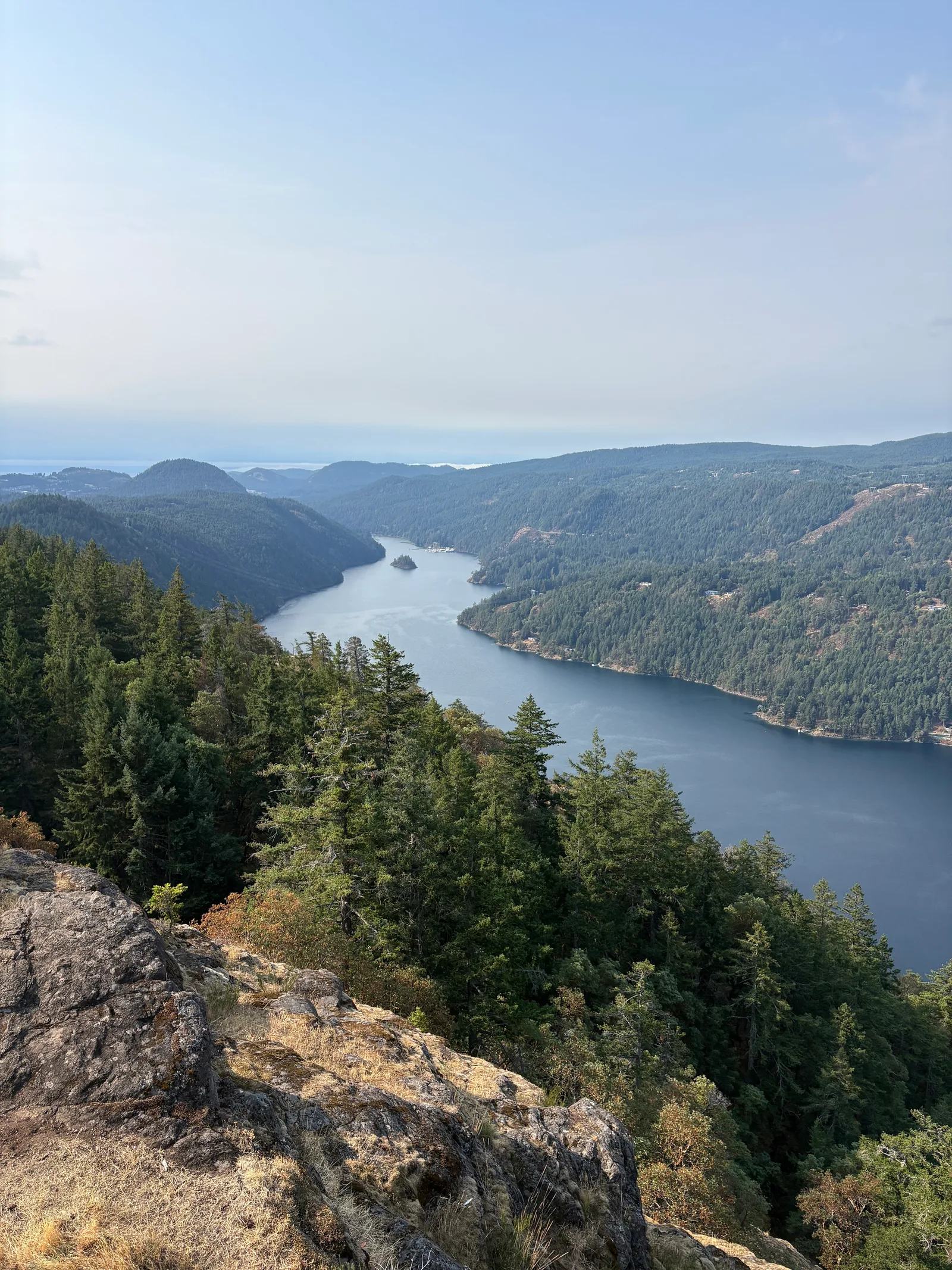 Panoramic view down Finlayson Arm from the Jocelyn Hill ridge, with forested slopes dropping to the water and mountains layered in the distance