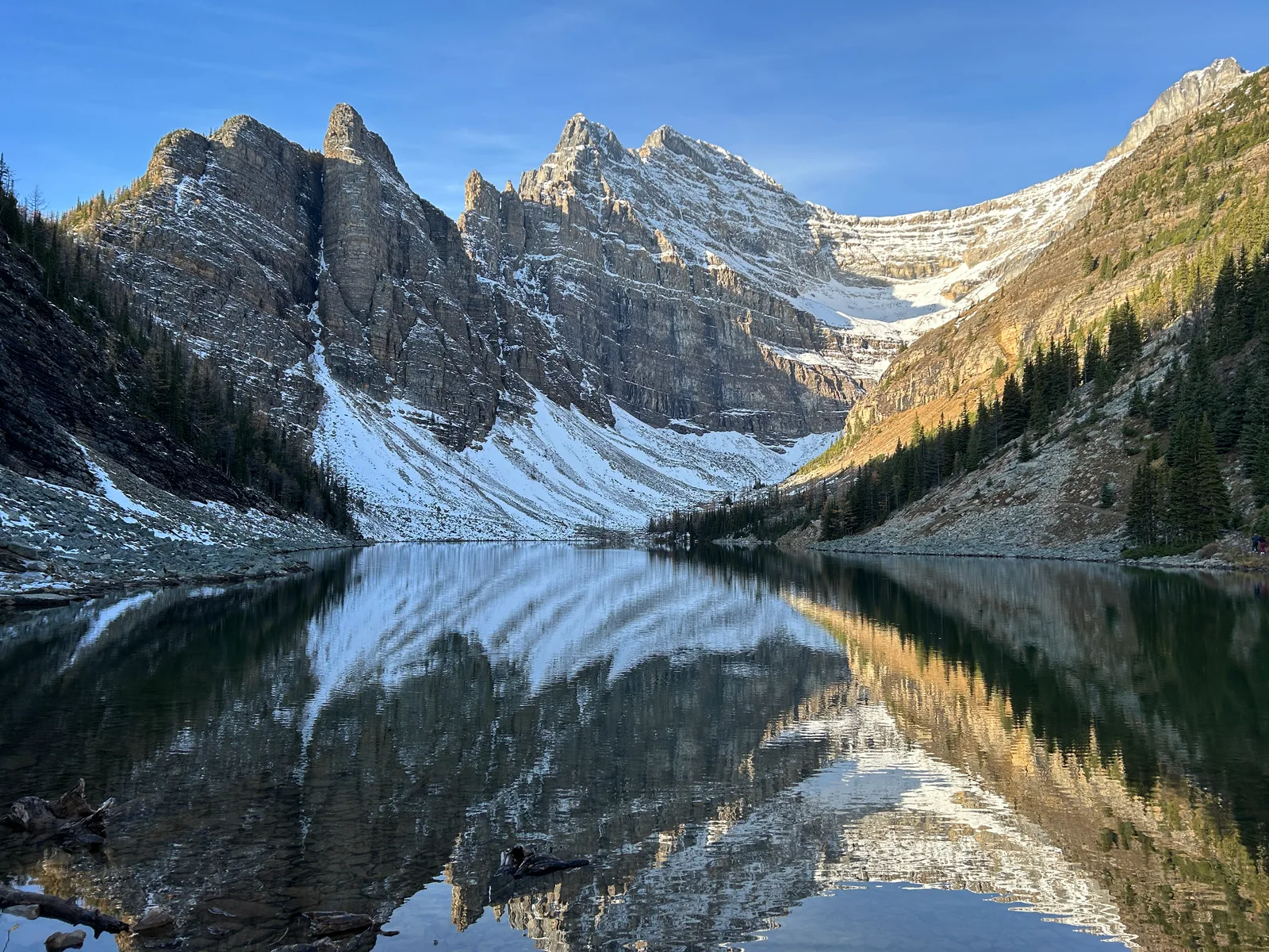 Lake Agnes with the jagged Beehive rock towers reflected in the still water, snow dusting the upper slopes